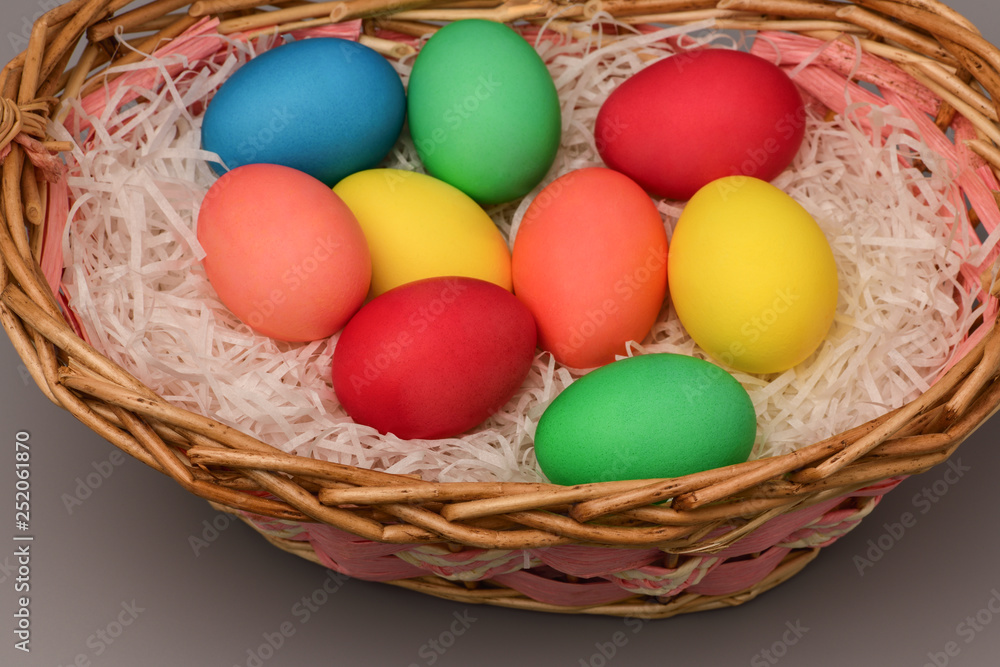 Top view of Easter colorful eggs in basket on grey background
