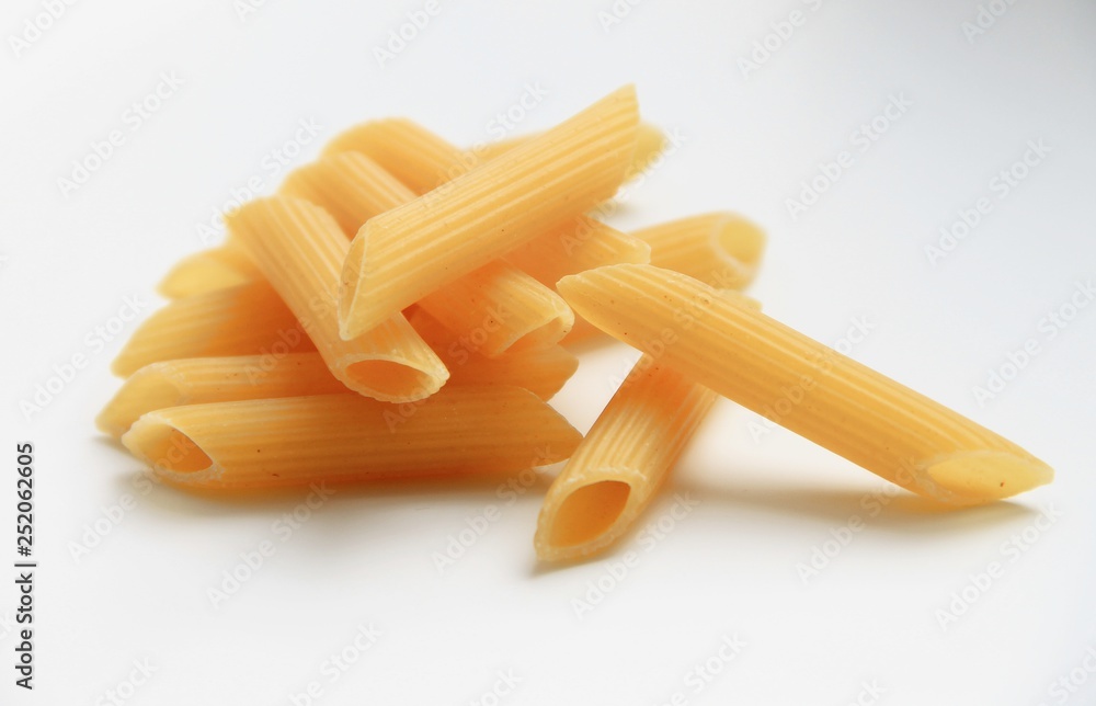 Yellow uncooked pasta are on a white background. Yellow uncooked pasta are on a white background.