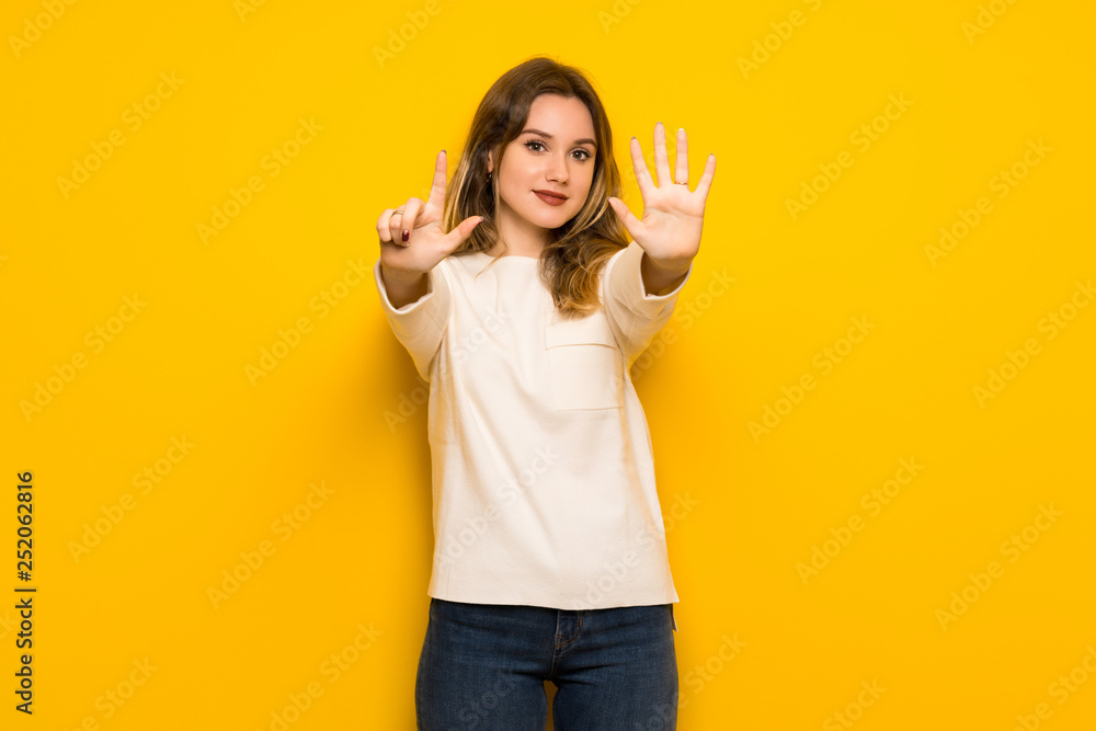 Teenager girl over yellow wall counting seven with fingers Teenager girl over yellow wall counting seven with fingers