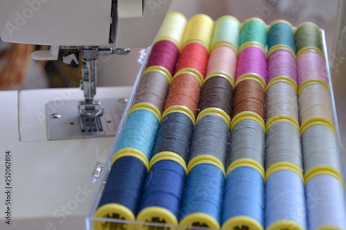 Colorful treads for sewing.Sewing supplies and accessories for needlework- scissors, needles, yellow measuring tape, thread on a table. Close up group of Multicolored spools of thread use to sewing.