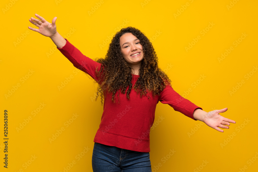 Teenager girl with red sweater over yellow wall presenting and inviting to come with hand Teenager girl with red sweater over yellow wall presenting and inviting to come with hand