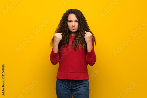 Teenager girl with red sweater over yellow wall frustrated by a bad situation