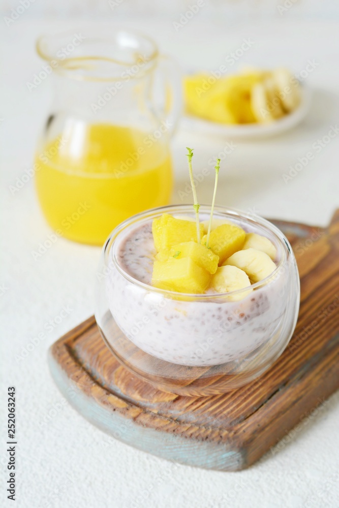 Chia pudding with mango pulp in beautiful glasses with green mint leaves and cut fresh ripe tropical fruit, orange juice for breakfast on a light background - raw vegetarian sweet organic dessert. Chia pudding with mango pulp in beautiful glasses with green mint leaves and cut fresh ripe tropical fruit, orange juice for breakfast on a light background - raw vegetarian sweet organic dessert.