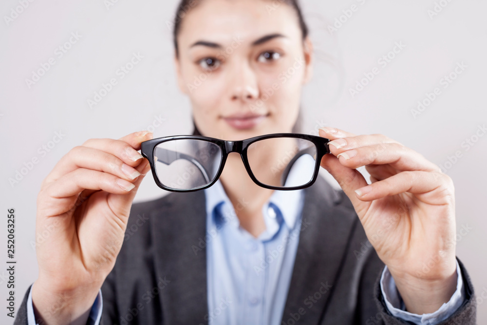 Fototapeta premium Businesswoman holding eyeglasses in hands on gray background