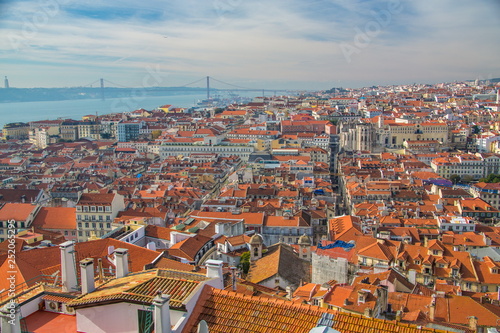 View of the streets and the orange roofs of the old town. Lisbon, Portugal. In the distance, see the bridge of April 25 and the statue of Christ. View from the walls of the castle of St. George