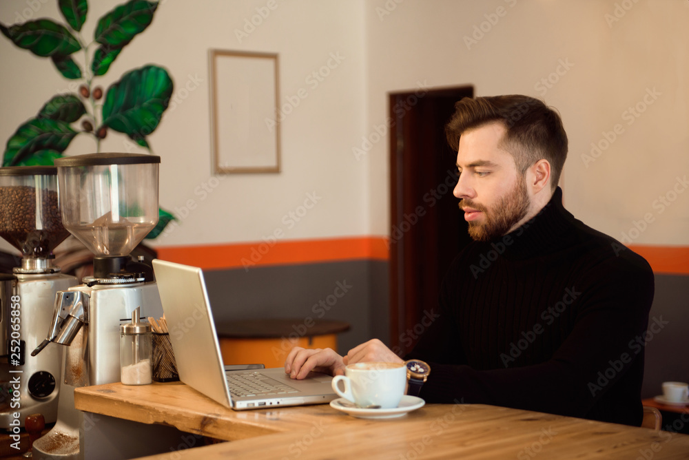 Businessman using laptop with tablet on wooden table in coffee shop with a cup of coffee. Businessman using laptop with tablet on wooden table in coffee shop with a cup of coffee.
