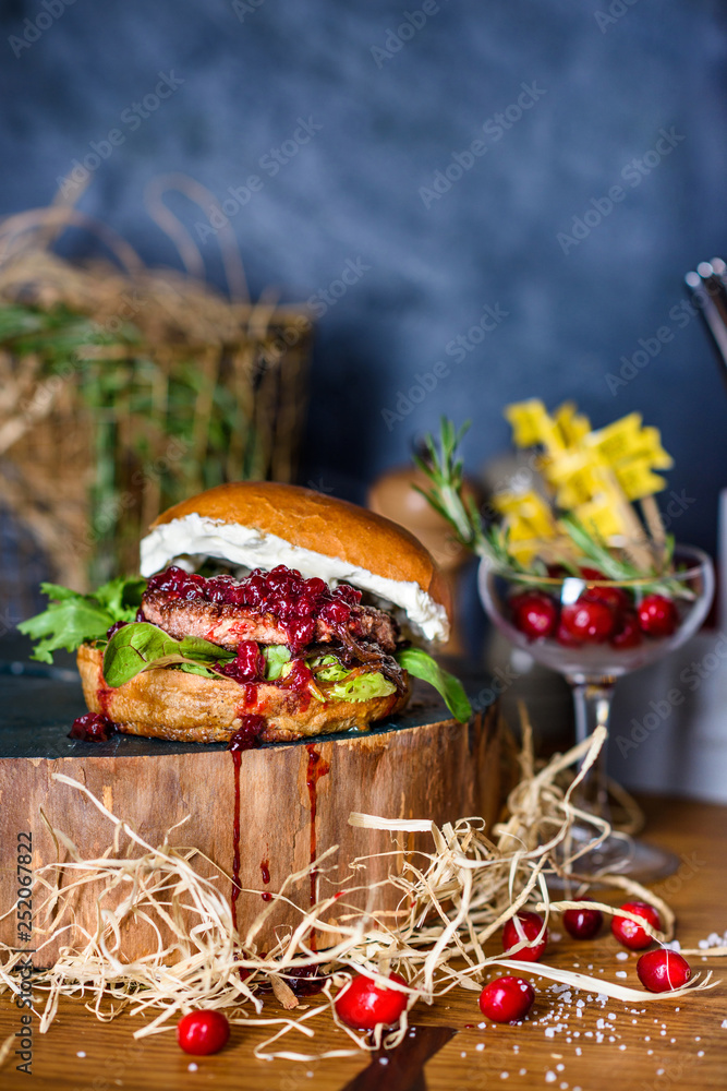 Delicious burger with beef, cheese and cranberry sauce on wooden counter.