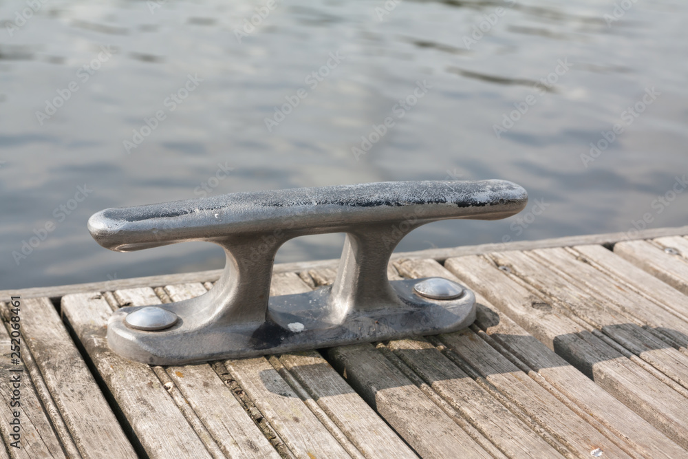 Mooring hook on wooden pier on the river in Finland at summer sunny day.