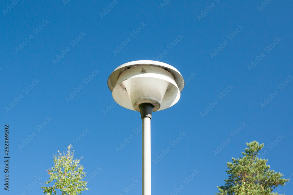 Street lamp and trees on clear sky background.
