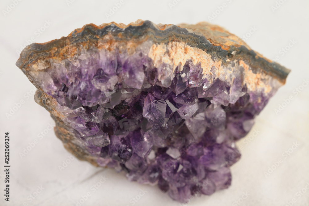 Beautiful amethyst druse close-up on white cement background. Semi precious gem used for jewels.