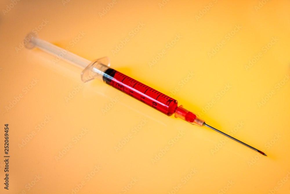 Fototapeta premium Syringe with blood on orange background