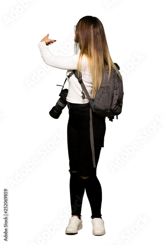 Full body of Young photographer woman pointing back with the index finger