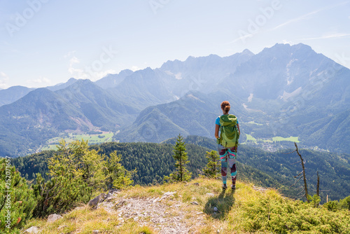 Young woman wearing backpack is admiring the valley view from top of a mountain. Travel and adventure concept. Healthy lifestyle and hiking concept. © blazekg