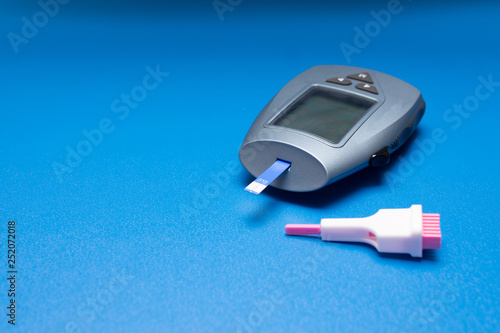 isolated digital glucometer with lancet and reactive strip on blue background