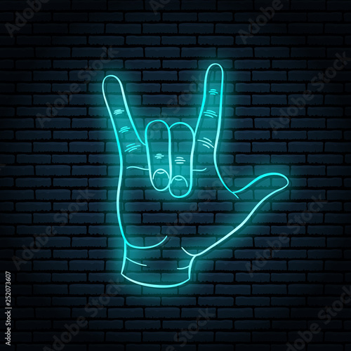 Neon sign with blue glow. Hand gesture, rock n roll. On a brick wall background, for your design.