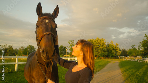 CLOSE UP: Girl looks at her muscular horse with a loving look in her eyes.