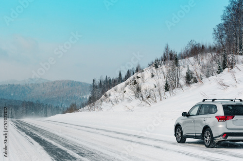 Suv car stay on roadside of winter road. Family trip to ski resort concept. Winter or spring holidays adventure. car on winter snowy road.