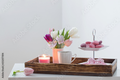 Tulips in vase and cup of coffee with dessert on white background. Concept woman's or mother's day
