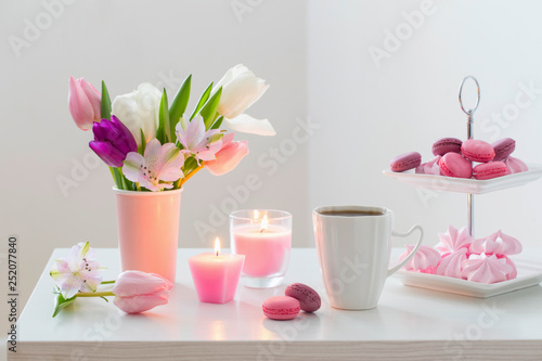 Tulips in vase and cup of coffee with dessert on white background. Concept woman's or mother's day