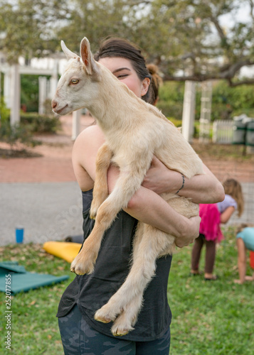 Goat Yoga with young woman holding goat like a baby