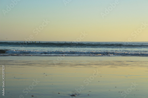 Group of surfers surfing on the beach  with sunset colors