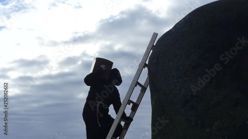 middle ages man in hoodie with chest climbing up to rock slow motion photo