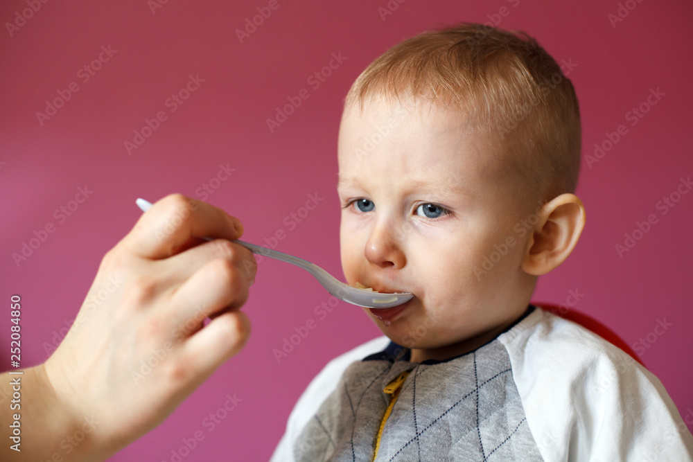 Mom feeds her beautiful baby with a spoon. Healthy Chicken Soup Mom feeds her beautiful baby with a spoon. Healthy Chicken Soup