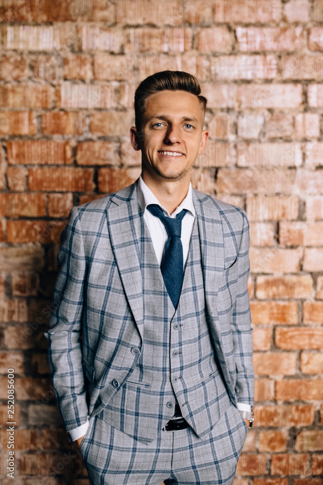 Young fashionable men in a suit against brick wall Young fashionable men in a suit against brick wall