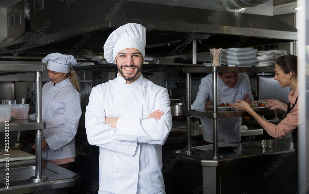 Chef in kitchen on background with employees