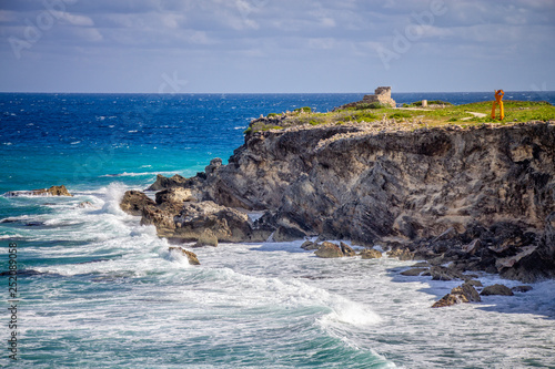 Waves crashing onto the rocks at Cliff of the Dawn. View of the southern most tip of Isla Mujeres. Punta Sur, Mexico. photo