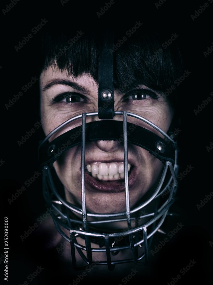 aggressive woman in dog muzzle looks into the camera. fierce facial expression. low key photography aggressive woman in dog muzzle looks into the camera. fierce facial expression. low key photography