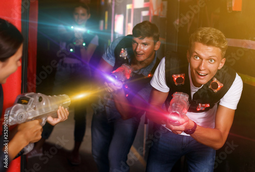 friends standing with laser guns during laser tag game