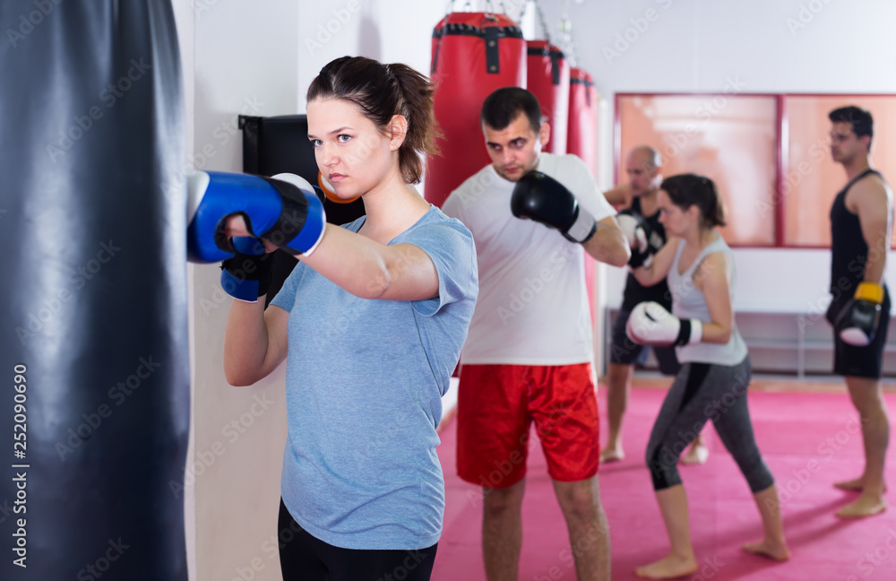 young sportswoman in the boxing hall practicing boxing punches with boxing bag