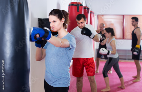 young sportswoman in the boxing hall practicing boxing punches with boxing bag © JackF