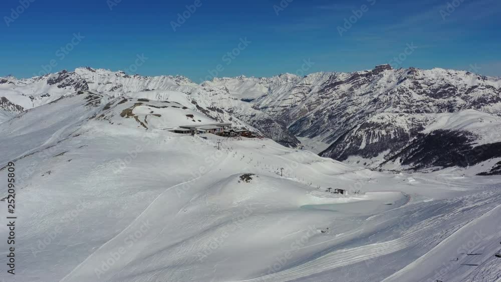 Aerial view of alpine skiers skiing downhill on ski slopes, hills covered with snow - Alps mountains in winter from above, ski resort Livigno, Italy, Europe Aerial view of alpine skiers skiing downhill on ski slopes, hills covered with snow - Alps mountains in winter from above, ski resort Livigno, Italy, Europe
