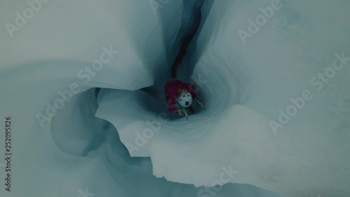 High angle view of ice climber ascending narrow crevice on glacier using hooks / Palmer, Alaska, United States