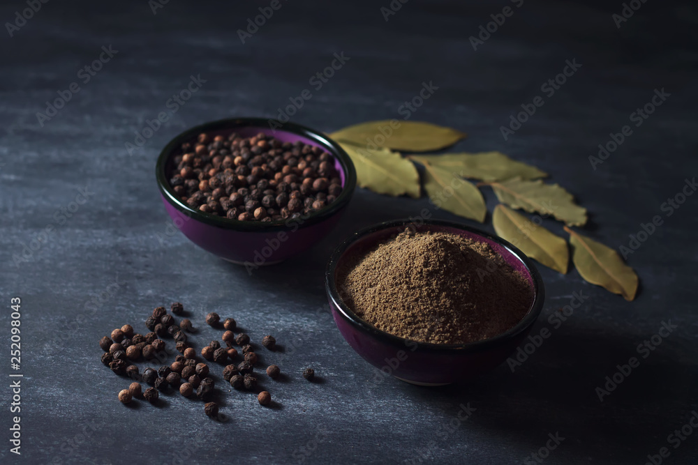 Ground black pepper and black peppercorns on a dark surface Ground black pepper and black peppercorns on a dark surface
