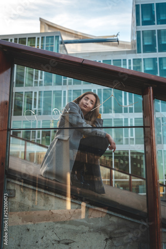Stylish woman sitting behind  slightly reflective glas