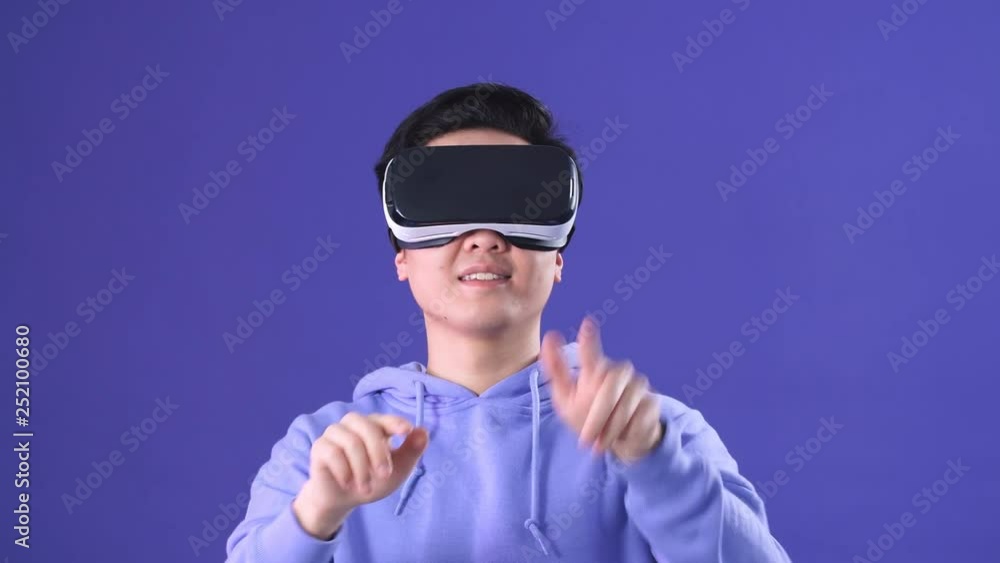 Future is right now. Young Man using 3D virtual reality headset. Virtual reality game. Man with pleasure uses head-mounted display. Young man playing game in virtual reality glasses. Future is right now. Young Man using 3D virtual reality headset. Virtual reality game. Man with pleasure uses head-mounted display. Young man playing game in virtual reality glasses.