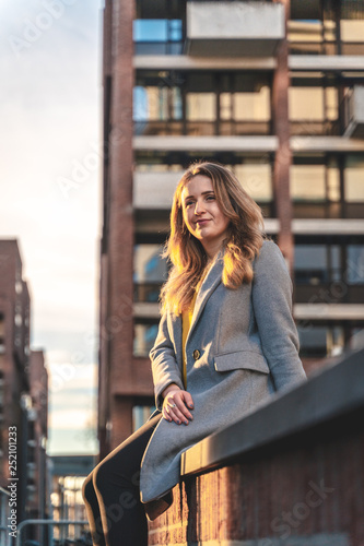 Young woman sitting in an urban environment during warm evening light