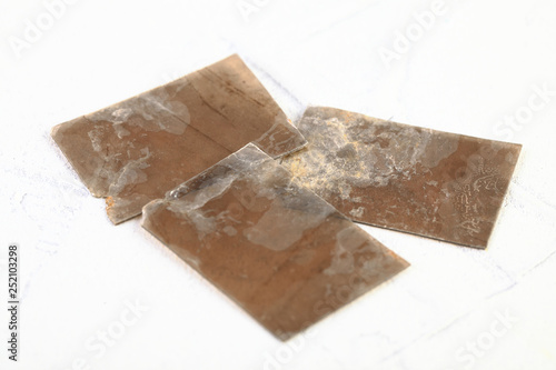 Natural mineral from geological collection - rough muscovite mica, common mica on white cement background from Poldnevoe, Ural, Russia.