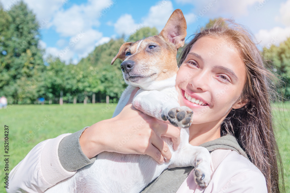 happy girl hugging on the hands with her dog for a walk in the park