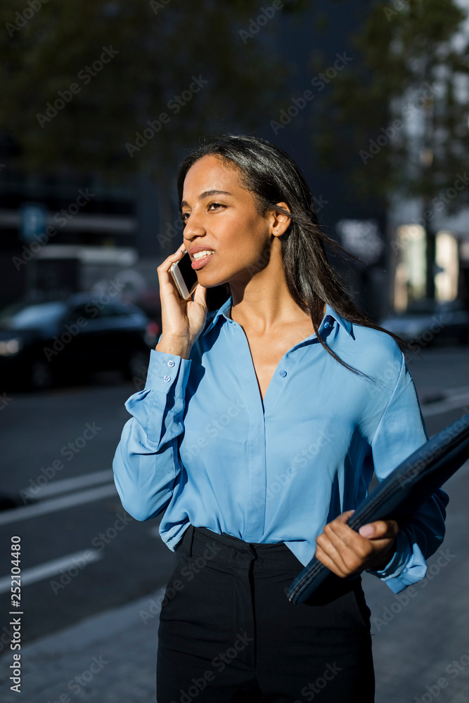Businesswoman using smartphone, laptop bag Businesswoman using smartphone, laptop bag