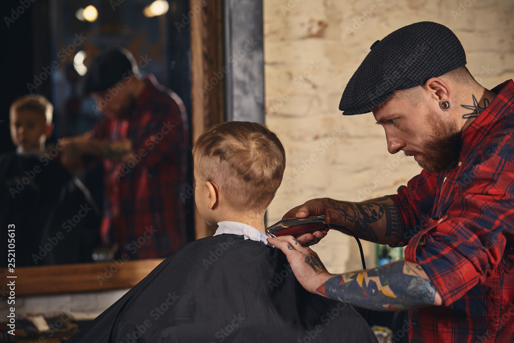 Caucasian boy getting haircut in barbershop indoor Caucasian boy getting haircut in barbershop indoor