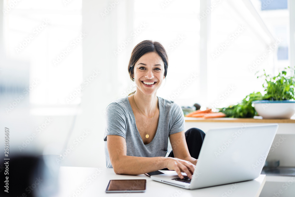 Happy woman sitting at desk, working from home, using laptop Happy woman sitting at desk, working from home, using laptop