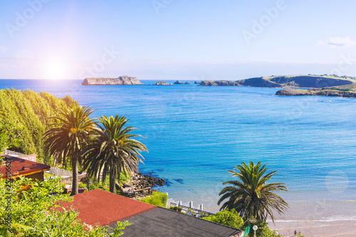 Blue sparkling sea water, green trees and resort town at sea and islands on horizon, opposite shore background. Tourism and vacations concept.