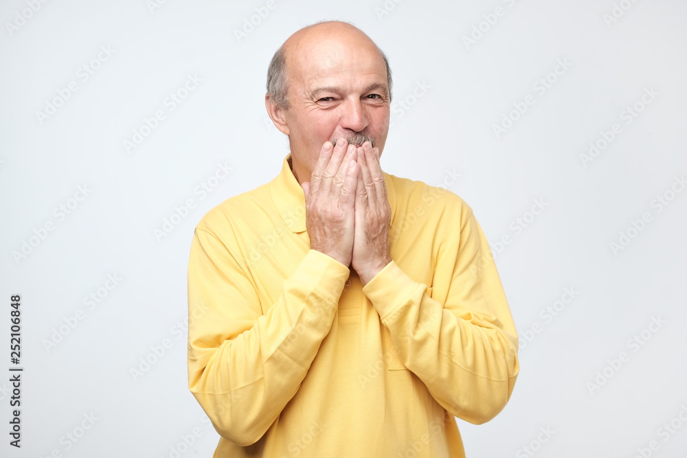 Mature bald man covering mouth and laughing. Mature bald man covering mouth and laughing.