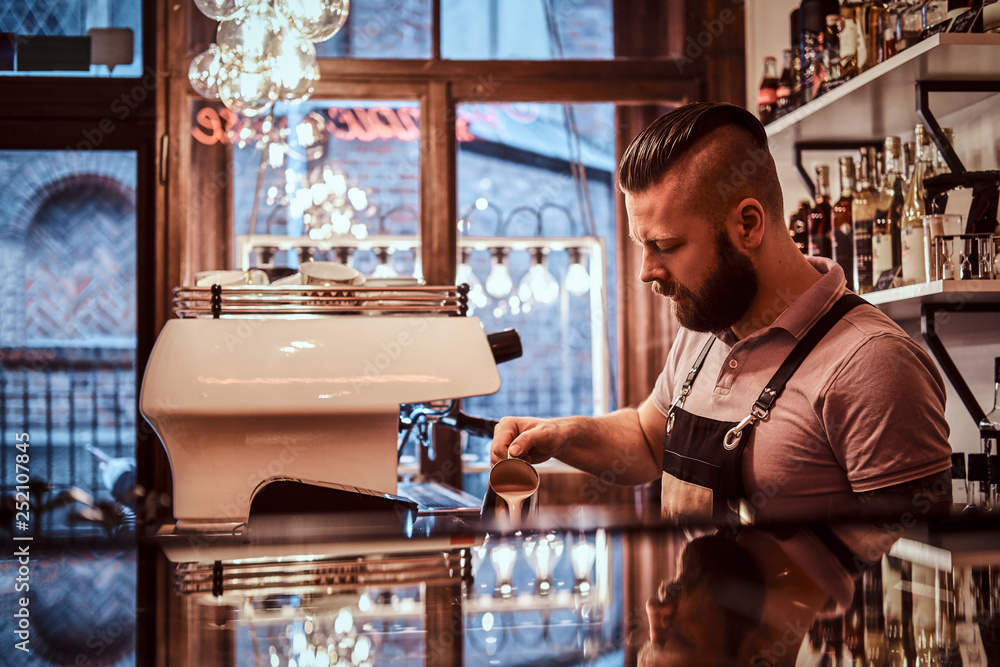 Barista in apron making a cappuccino, pouring milk in a cup in a restaurant or coffee shop