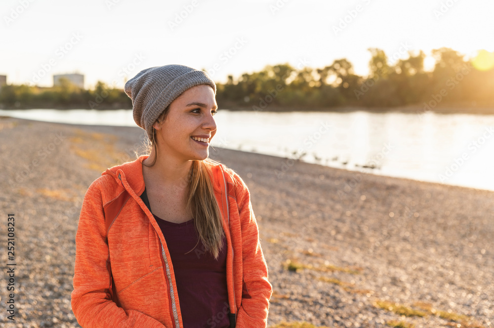 Portrait of a sportive young woman at the river, wearing a beanie hat
