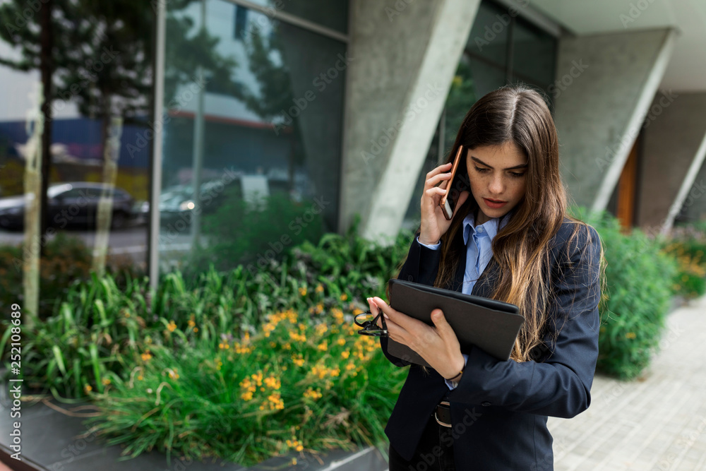 Young businesswoman using tablet and cell phone in the city Young businesswoman using tablet and cell phone in the city